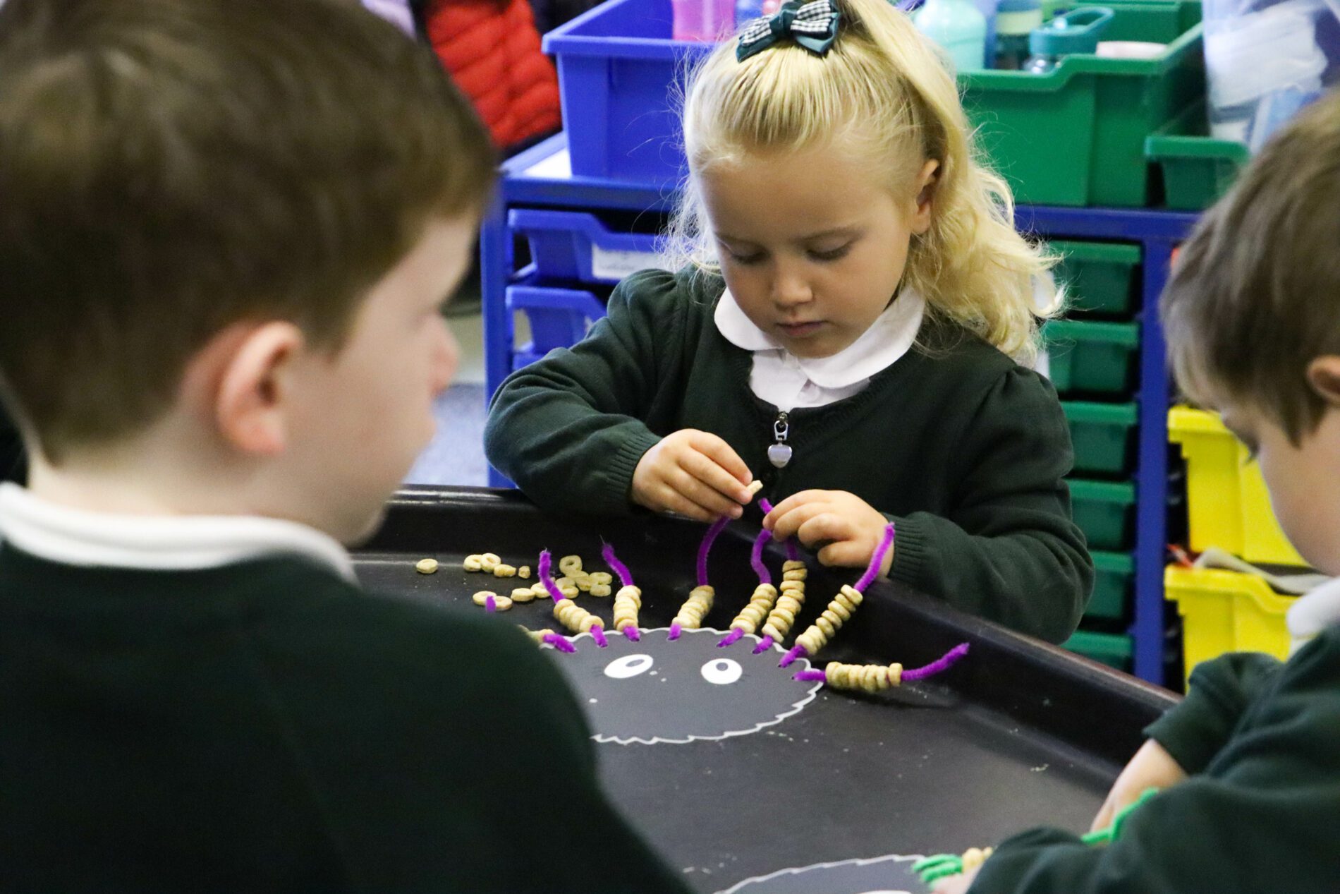 pupil in EYFS in a DT lesson making spiders out of cherrios