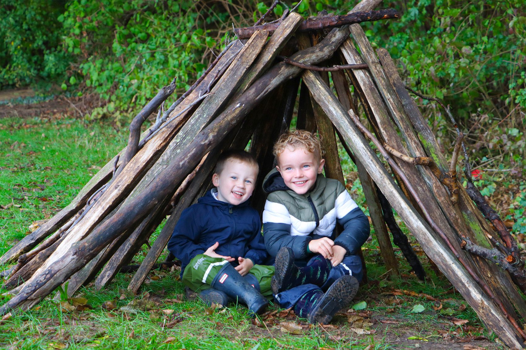 forest school at shorne primary school with two smiling kids underneath a wood structure